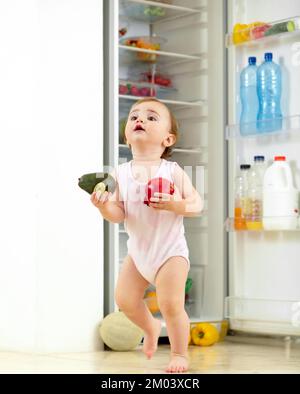 Leaving the scene of the crime. a toddler eating food from the fridge. Stock Photo