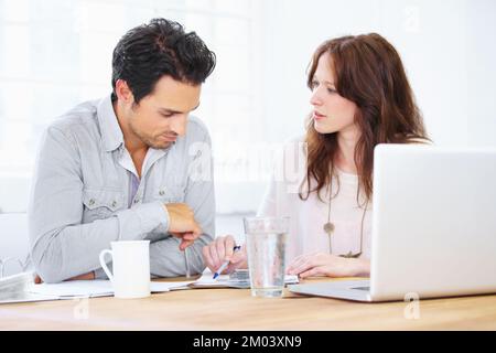 Their business savvy is legendary. a two young design professionals sitting together and discussing something on a laptop. Stock Photo