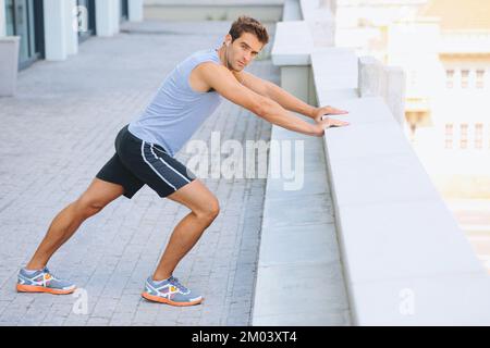 Preparing for his run. Young jogger doing some stretches outside. Stock Photo