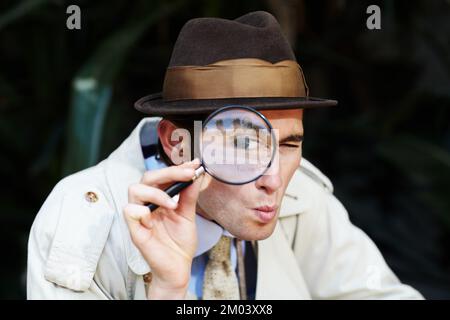 Finding all the clues. Curious private investigator looking through a magnifying glass. Stock Photo