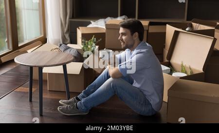 Happy thoughtful home owner man taking break from relocation activity Stock Photo