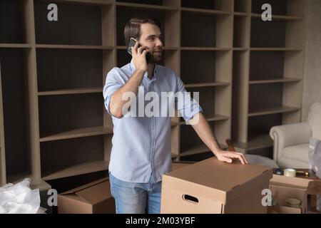Happy renter man, apartment buyer talking on mobile phone Stock Photo