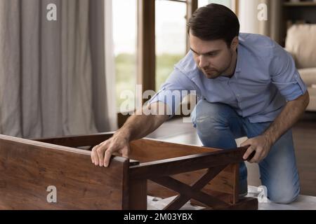 Serious professional handyman working on wooden table Stock Photo