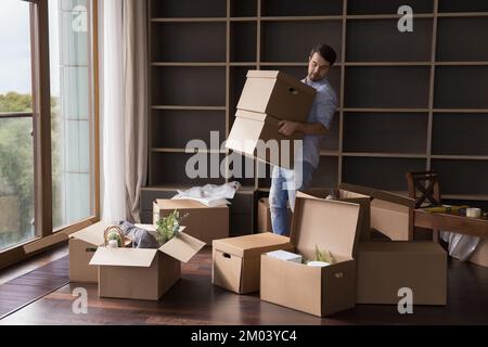 Busy serious renter man carrying stack of paper cardboard boxes Stock Photo