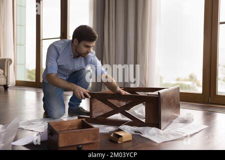 Focused serious homeowner man assembling new piece of furniture Stock Photo