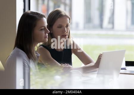 Two young business women work on presentation using modern laptop Stock Photo