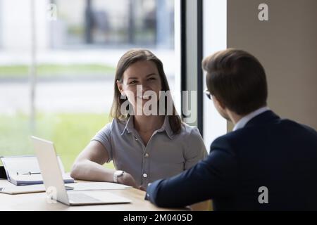 Colleagues communicating seated at desk in modern workspace Stock Photo