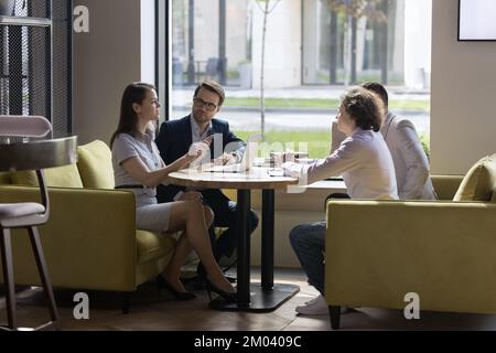 Four millennial businesspeople negotiating in modern office Stock Photo