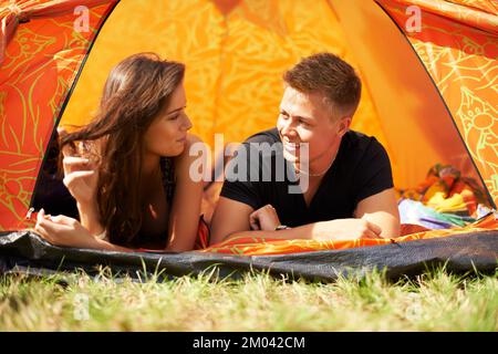 Talking in the tent. a young couple lying in a tent together. Stock Photo