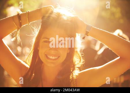 The light emphasizing her. A beautiful young woman backlit by a bright sun at a music festival. Stock Photo
