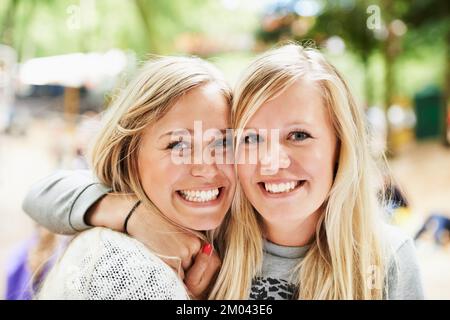 We go everywhere together. Portrait of a two young blonde friends embracing while outside at a festival. Stock Photo