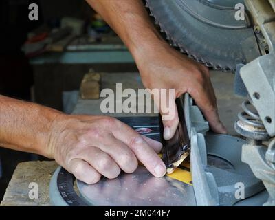 working with a miter saw in a carpenter's workshop, close-up, cutting a wooden fillet on a circular machine Stock Photo