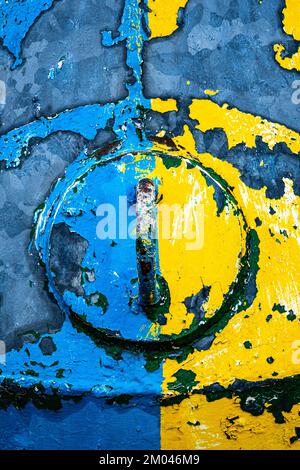 Peeling yellow and blue paint and rust on an aged buoy Stock Photo