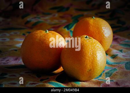 three tangerines on a colored tea towel Stock Photo