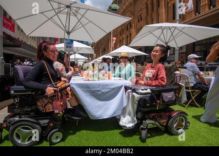 Two women in motorised wheelchairs smile and enjoy the day at Sydney’s 2022 Open For Lunch in Australia event held in George Street Stock Photo