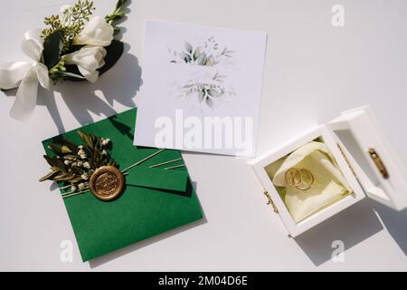Top view of wedding rings on oaths. A wooden box for wedding rings. Beautiful boutonniere on table Stock Photo