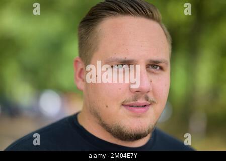 Young man in his twenties with a thoughtful expression looking to the side in a close up head shot Stock Photo