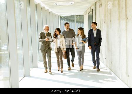 Group of corporate business professionals walking through office corridor on a sunny day Stock Photo