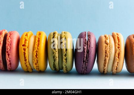 colored macaroons in a row on a blue background Stock Photo