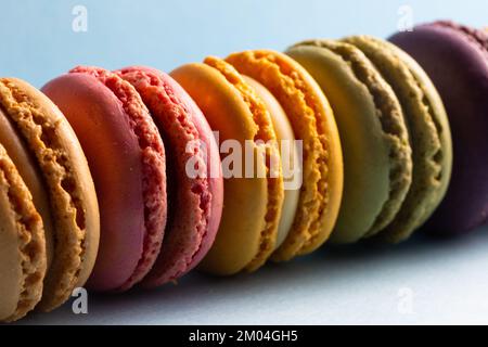 colored macaroons in a row on a blue background Stock Photo