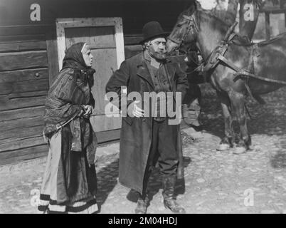 Theatre in the 1930s. An elderly couple dressed up in historical clothes are performing something for an audience outdoors. An old house and a horse is seen in the background. 20 may 1939. Sweden Stock Photo