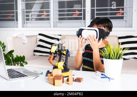 Asian kid boy using VR glasses on robotic arm in workshop Stock Photo
