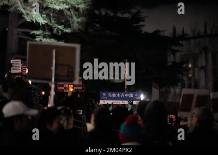 Washington, University District, USA. 28th Nov, 2022. A protester seen holding the ''Urumqi Middle Road'' street sign that symbolizes the origin of the movement during the demonstration. At the University of Washington, more than two hundred people gathered to show solidarity with the ''white paper'' protest in China. The protesters called on the Chinese government to release all the protesters, free China, and ask President Xi to step down. However, protesters lit a candle to symbolize a tragedy under excessive control to show their support for the Urumqi fire tragedy. This trage Stock Photo