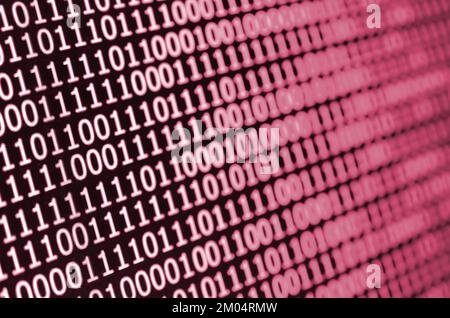 Macro shot of binary code on the monitor of an office computer. The concept of the programmer's work. The flow of digital information strings. Image toned in Viva Magenta, color of the 2023 year Stock Photo