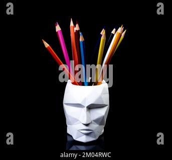 Color pencils for the drawing, located in a support as a vase, focus in front. multi-colored pencils and felt-tip pens in a plaster vase in the shape Stock Photo
