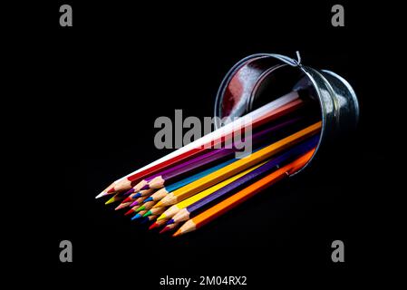 multi-colored pencils in a wine glass and a bucket. Selective blurred a group of coloring pencils in a wine glass on the isolated white or black backg Stock Photo