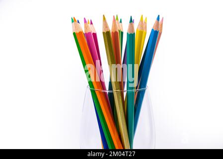 multi-colored pencils in a wine glass and a bucket. Selective blurred a group of coloring pencils in a wine glass on the isolated white or black backg Stock Photo