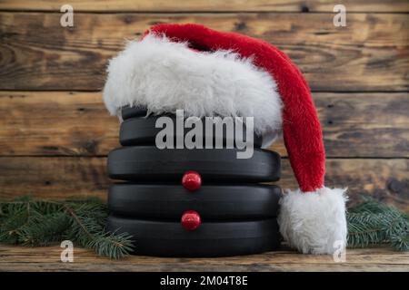 Dumbbell barbell weight plates in shape of snowman, with red Santa Claus Christmas hat. Healthy fitness composition. Gym workout training concept. Stock Photo