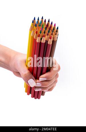 Multi-colored pencils for drawing in a female hand. multi-colored pencils in female hand on white background, Close up, copy space, Modern art. Modern Stock Photo