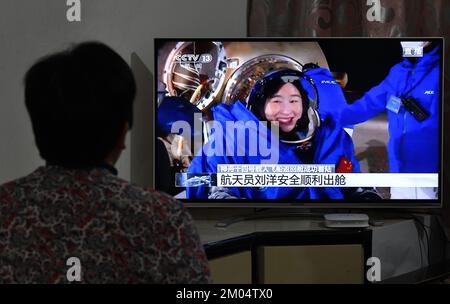 FUYANG, CHINA - DECEMBER 4, 2022 - Citizens watch a live TV broadcast of the re-entry module of the Shenzhou 14 manned spacecraft landing at Dongfeng Stock Photo