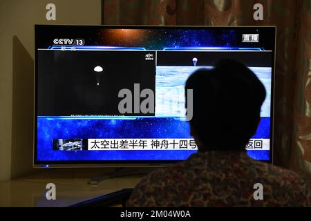 FUYANG, CHINA - DECEMBER 4, 2022 - Citizens watch a live TV broadcast of the re-entry module of the Shenzhou 14 manned spacecraft landing at Dongfeng Stock Photo