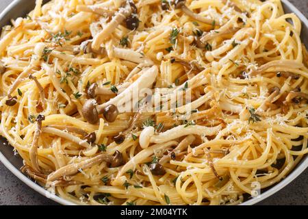Creamy spaghetti with beech mushrooms with parmesan and thyme close-up in a plate on the table. horizontal Stock Photo