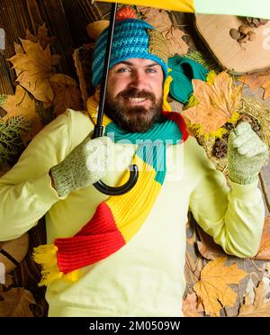 Fall atmosphere attributes. Rainy weather forecast concept. Hipster wear knitted hat and gloves expect rainy weather hold umbrella. Man bearded lay on Stock Photo