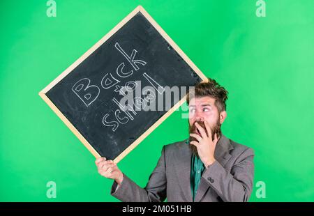Keep working. Teacher with tousled hair stressful about school year beginning. Teaching stressful occupation. Teacher bearded man holds blackboard Stock Photo