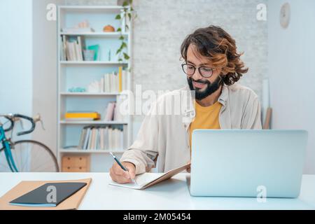 Man using laptop at home remote work in a small business. Handsome smiling male working in a project Stock Photo