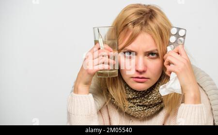 Woman wear warm scarf because illness or flu. Girl hold glass water tablets and thermometer light background close up. Get rid of flu. Getting fast Stock Photo