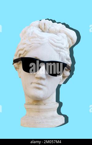 Antique sculpture female head in trendy sunglasses on an empty blue minimal background. Design, art, fashion, pop style concept. High quality photo Stock Photo