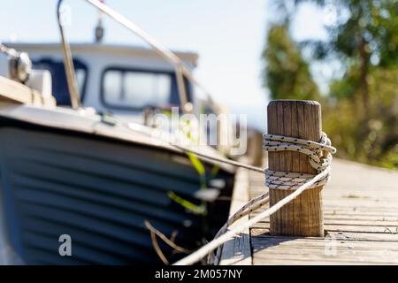 Yacht on a rope at the pier. Sea vessel is moored to an old wooden pier on a sunny summer day. High quality photo Stock Photo