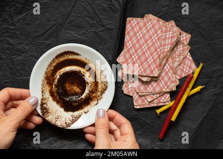 coffee grounds in the hands of a fortune teller and cards and candles on the table, fortune telling and prediction, fortune telling from coffee ground Stock Photo