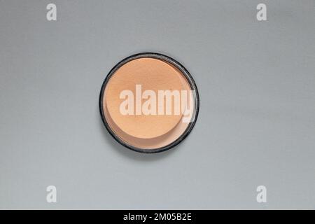 powder in a plastic round package on a gray background, women's cosmetics close-up, foundation powder Stock Photo