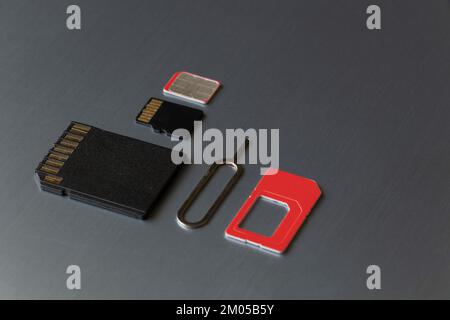 SIM card and paper clip to open the SIM card slot and the memory card are on a gray steel background Stock Photo