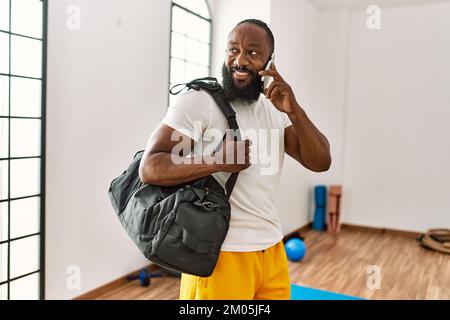 Young african american man holding gym bag talking on the smartphone at sport center Stock Photo