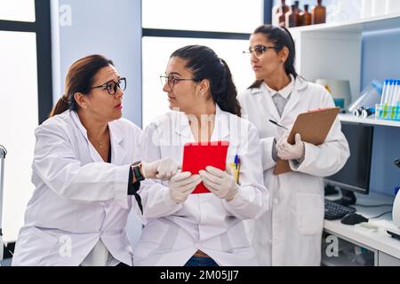 Three woman scientists using touchpad write on checklist at laboratory Stock Photo