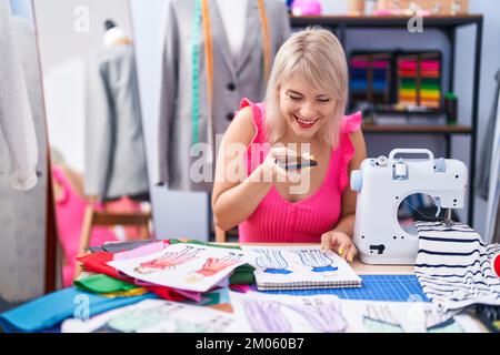 Young blonde woman tailor make photo by smartphone to clothing design at gaming room Stock Photo