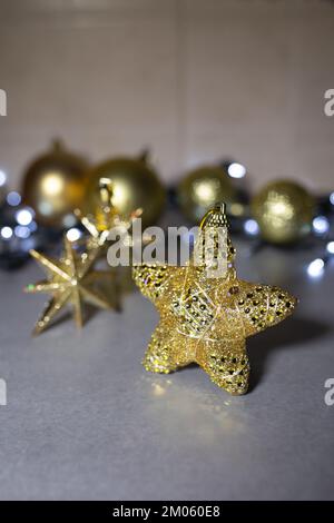 Christmas background with a golden star. New Year's decor. Christmas toy golden star and other toys on a gray background. Stock Photo
