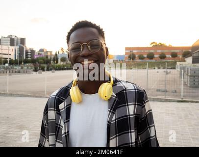 Portrait of a smiling young african american man with headphones looking at camera in a city Stock Photo